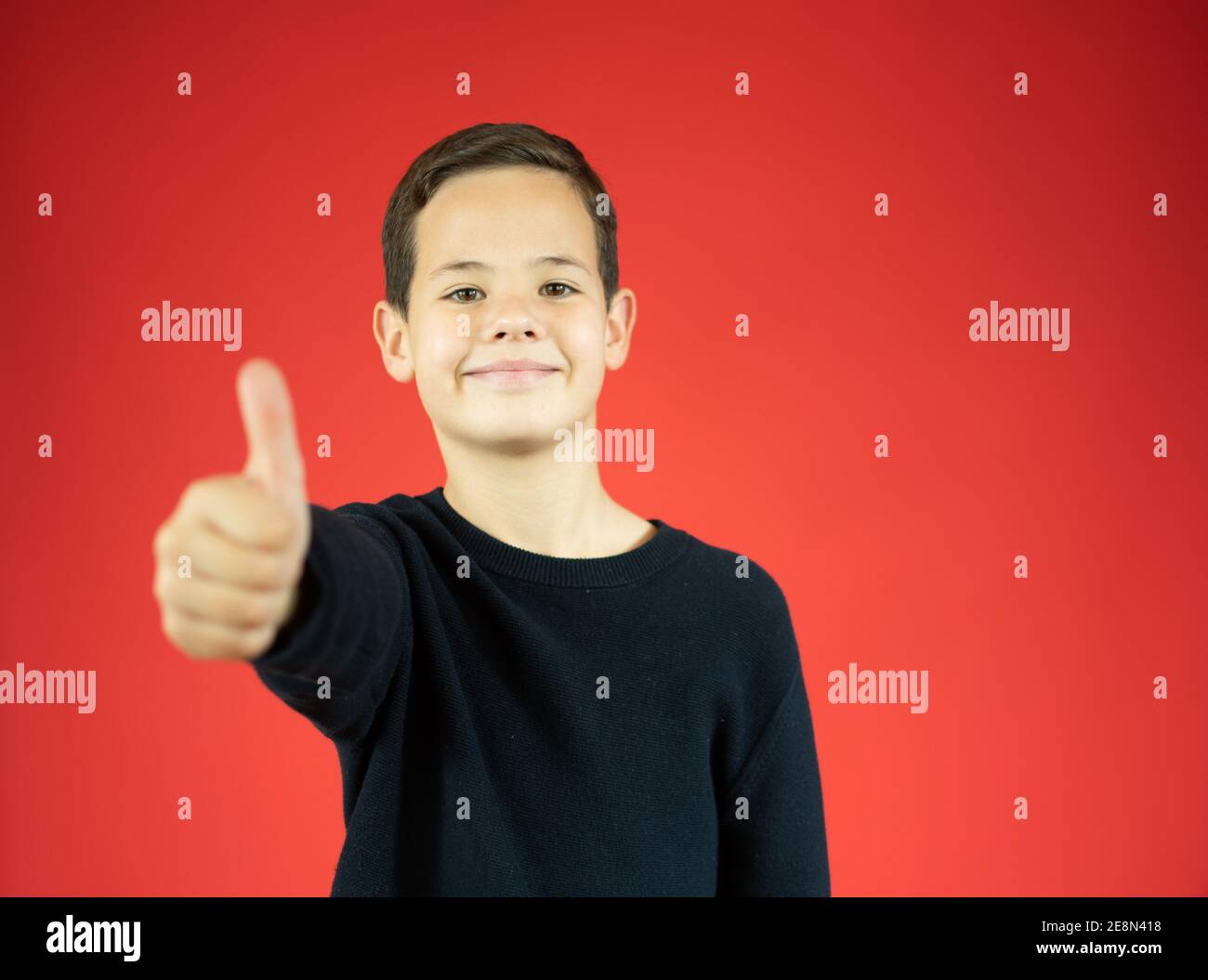Portrait of a smiling boy showing thumbs up isolated over red ...