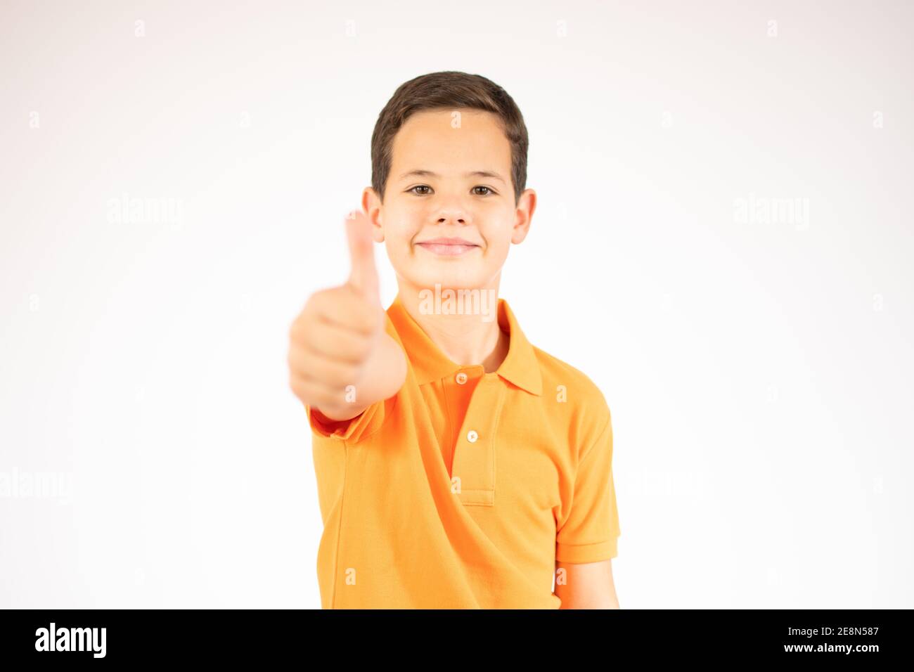 Portrait of a smiling boy showing thumbs up isolated over white ...