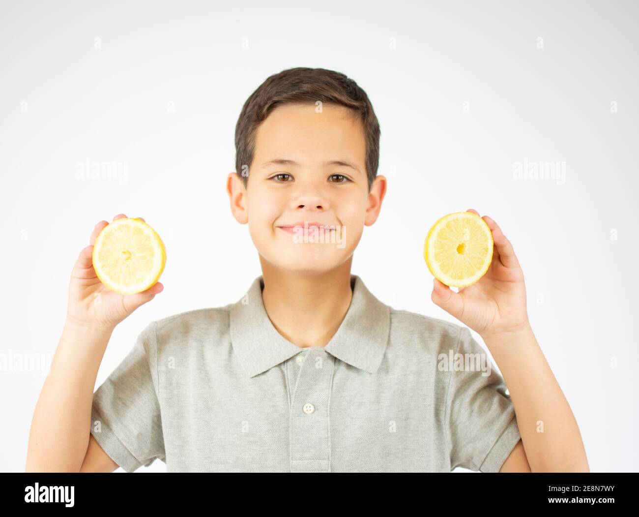 Portrait of lovely caucasian young boy shows two lemon slices.Boy look to a camera. Stock Photo