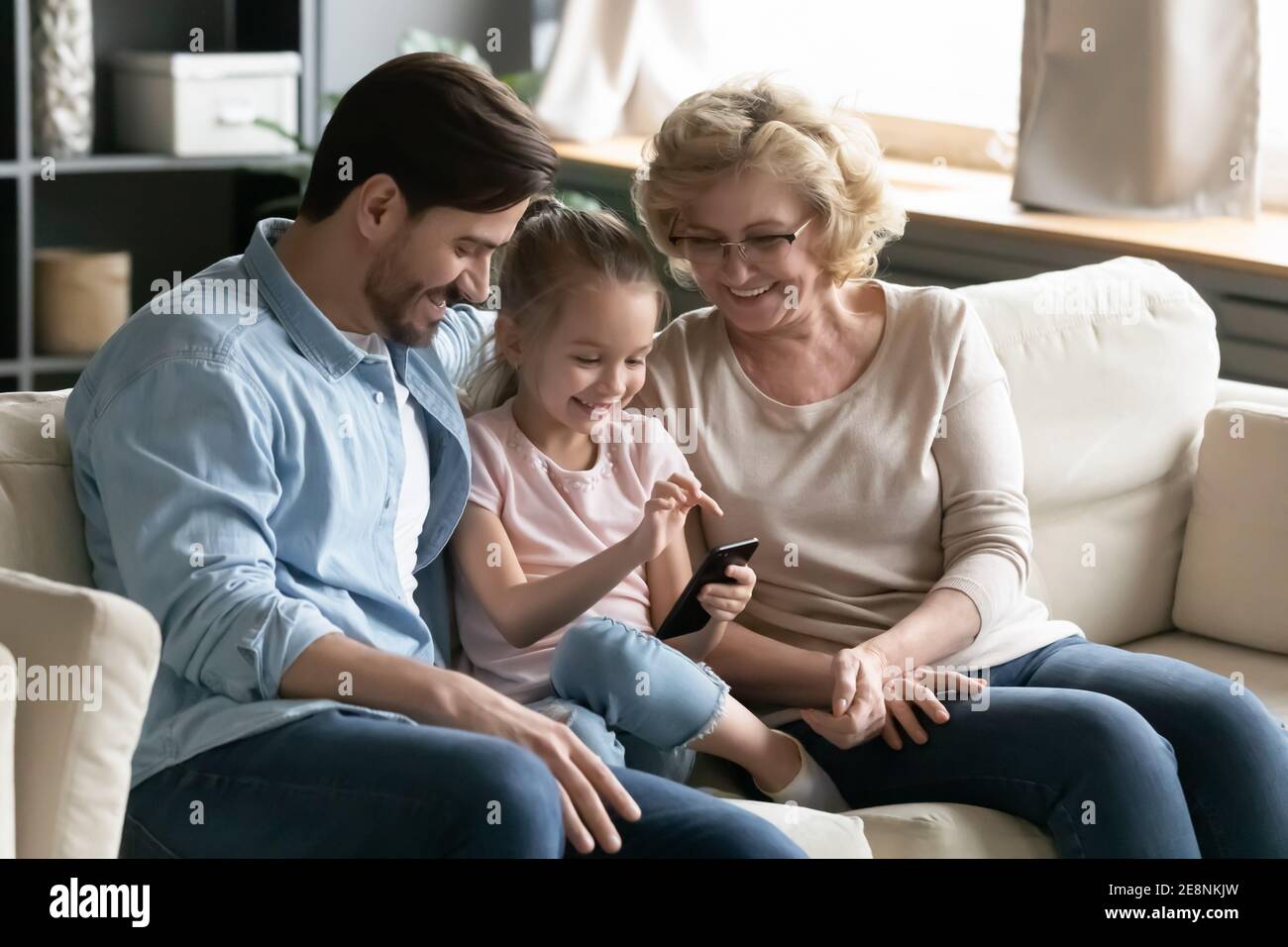 Happy different generations family using smartphone at home Stock Photo ...
