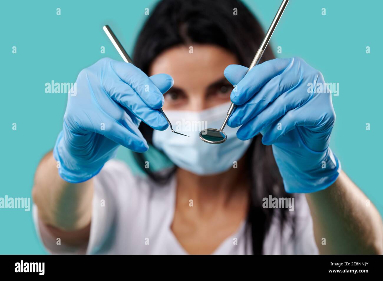 Closeup of dental metal tools in the hands of dentist woman on a blue background Stock Photo