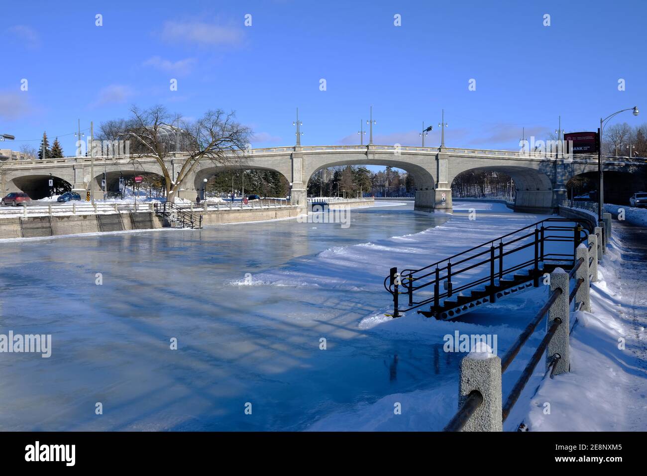 Bank Street bridge over a frozen Rideau Canal almost ready for skating on a sunny but freezing mid-winter's day in Ottawa, Ontario, Canada. Stock Photo
