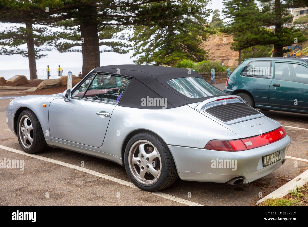 1995 Porsche Carrera 4 soft top sports car in grey silver parked by a Sydney beach in Australia Stock Photo