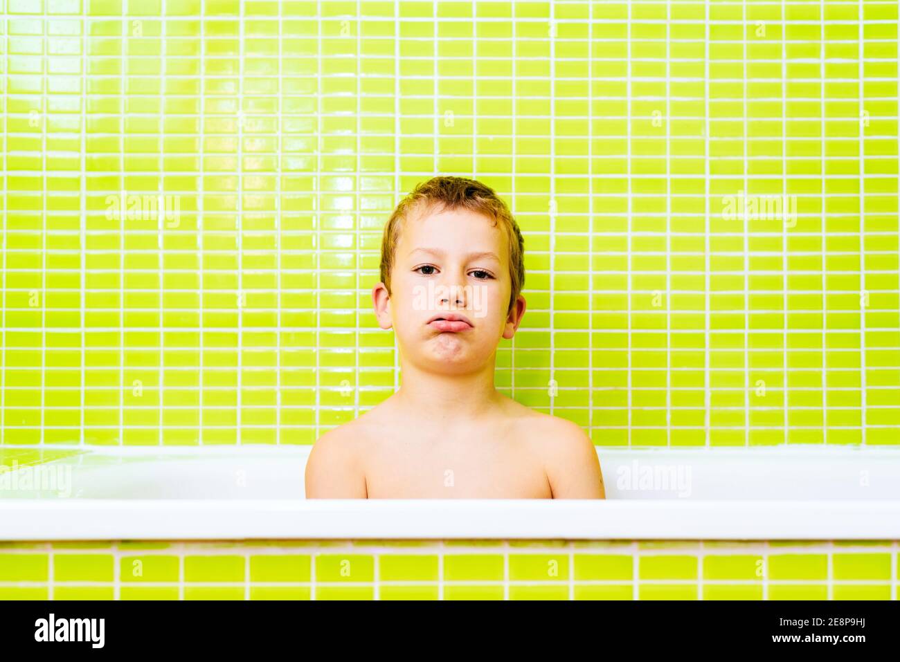 Child inside a bathtub does not want to bathe, and looks with an angry