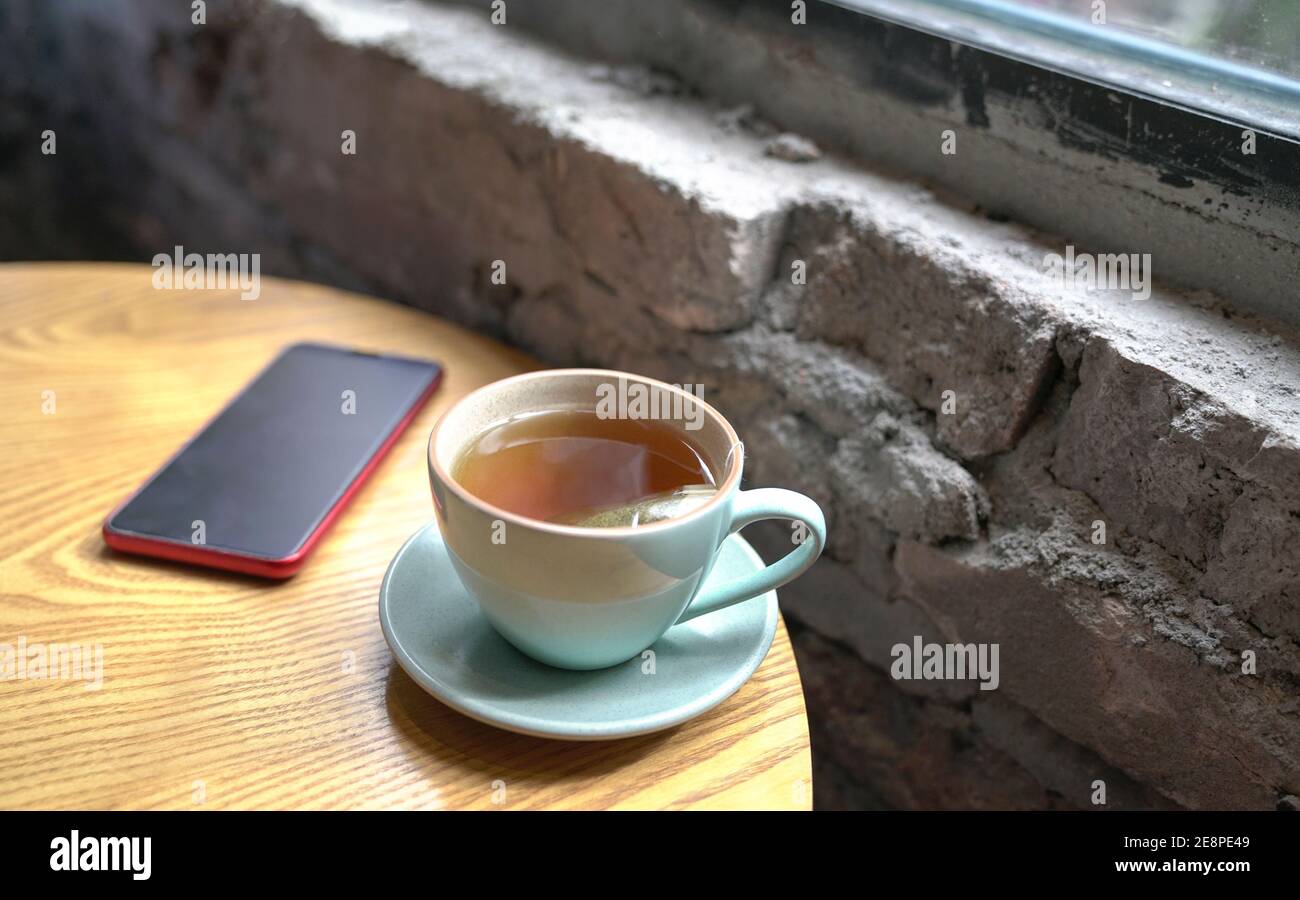 Cup of hot tea and cellphone on wood table, next to windows Stock Photo ...