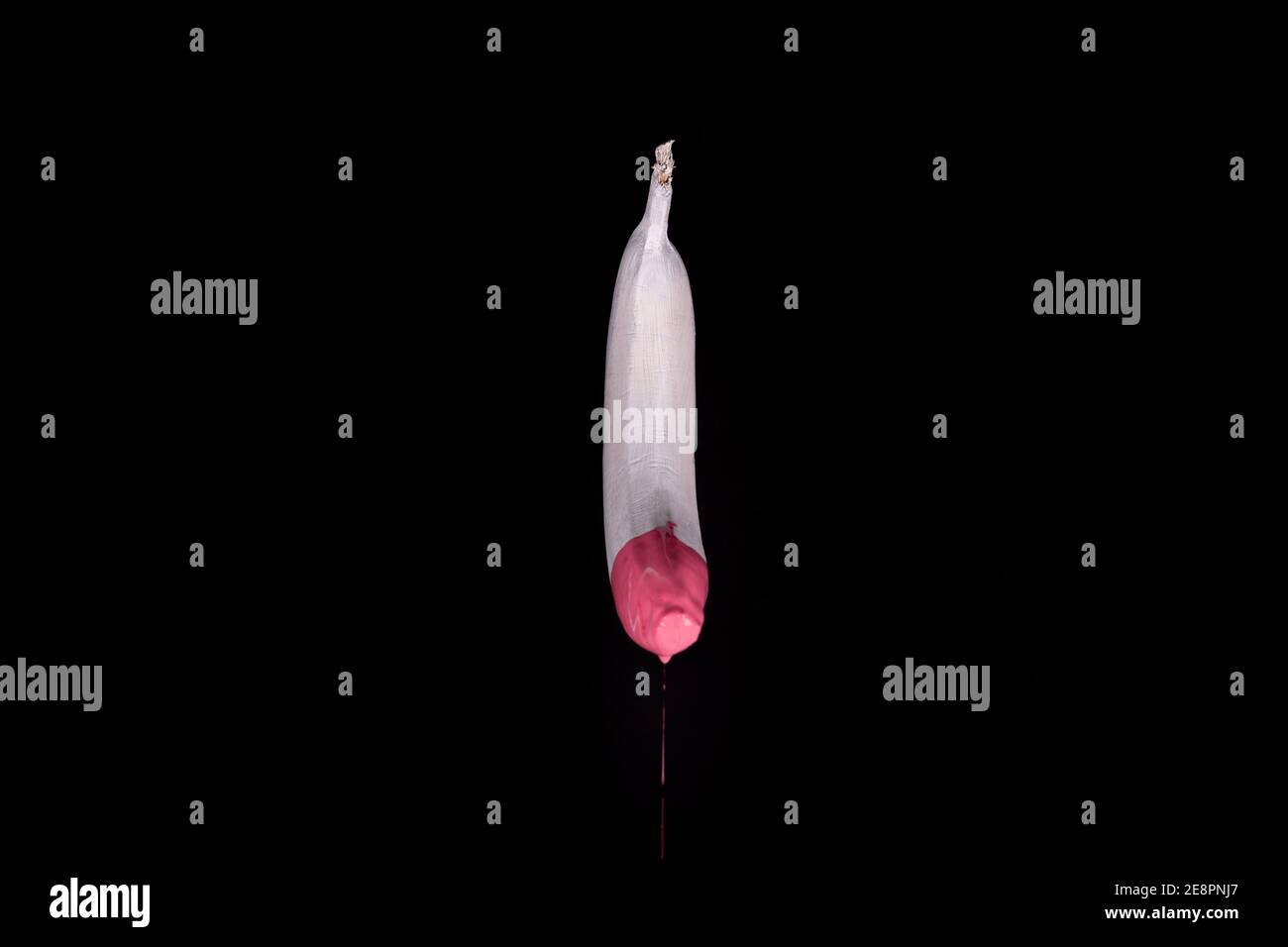 White floating banana with pink dripping paint. Black background. Creative food concept Stock Photo