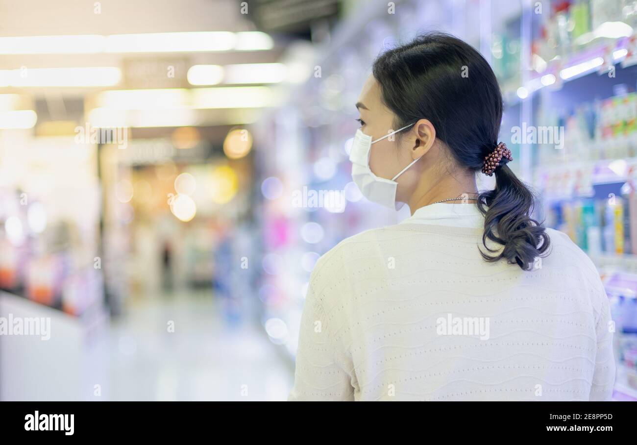 Asian woman wearing surgical mask shopping and walking in the aisle of
