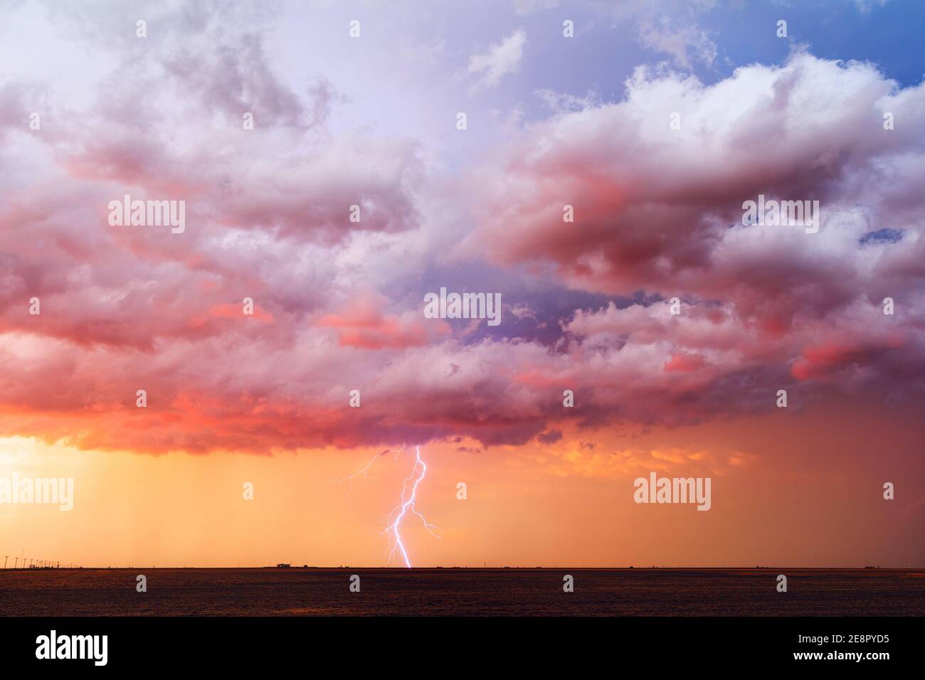 Stormy sunset sky with dramatic clouds and lightning strike as a thunderstorm approaches Perryton, Texas Stock Photo
