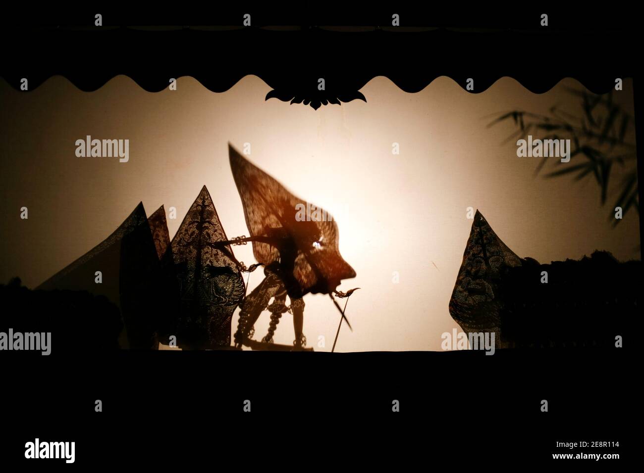 Indonesian puppet called wayang kulit performing on screen at night Stock Photo