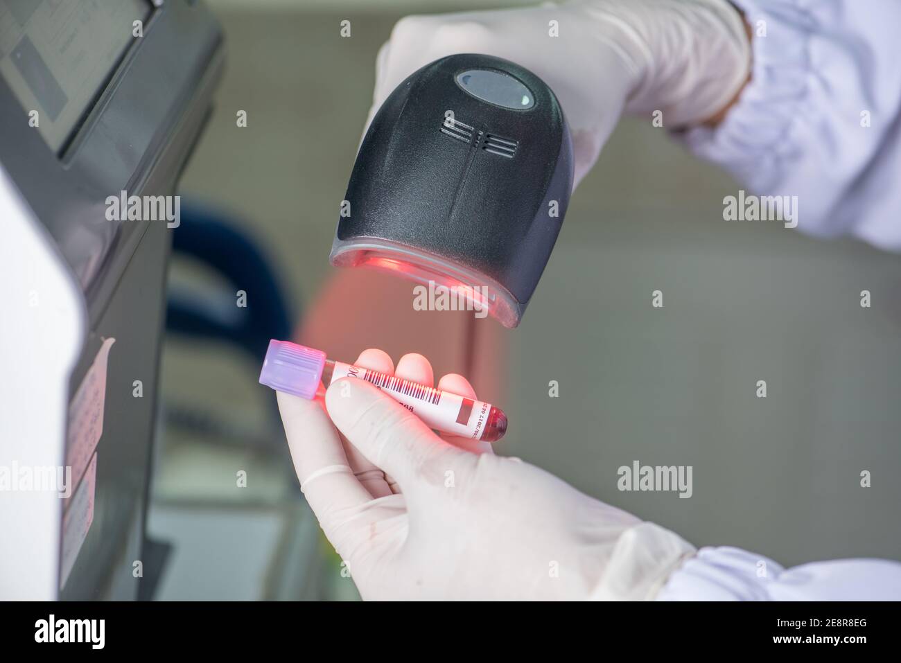 Technician scanning bar codes on biological sample tube in lab of blood