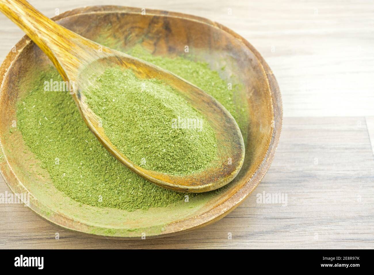 Kratom Mitragyna Speciosa an alternative medicine powder in wooden spoon bowl Stock Photo