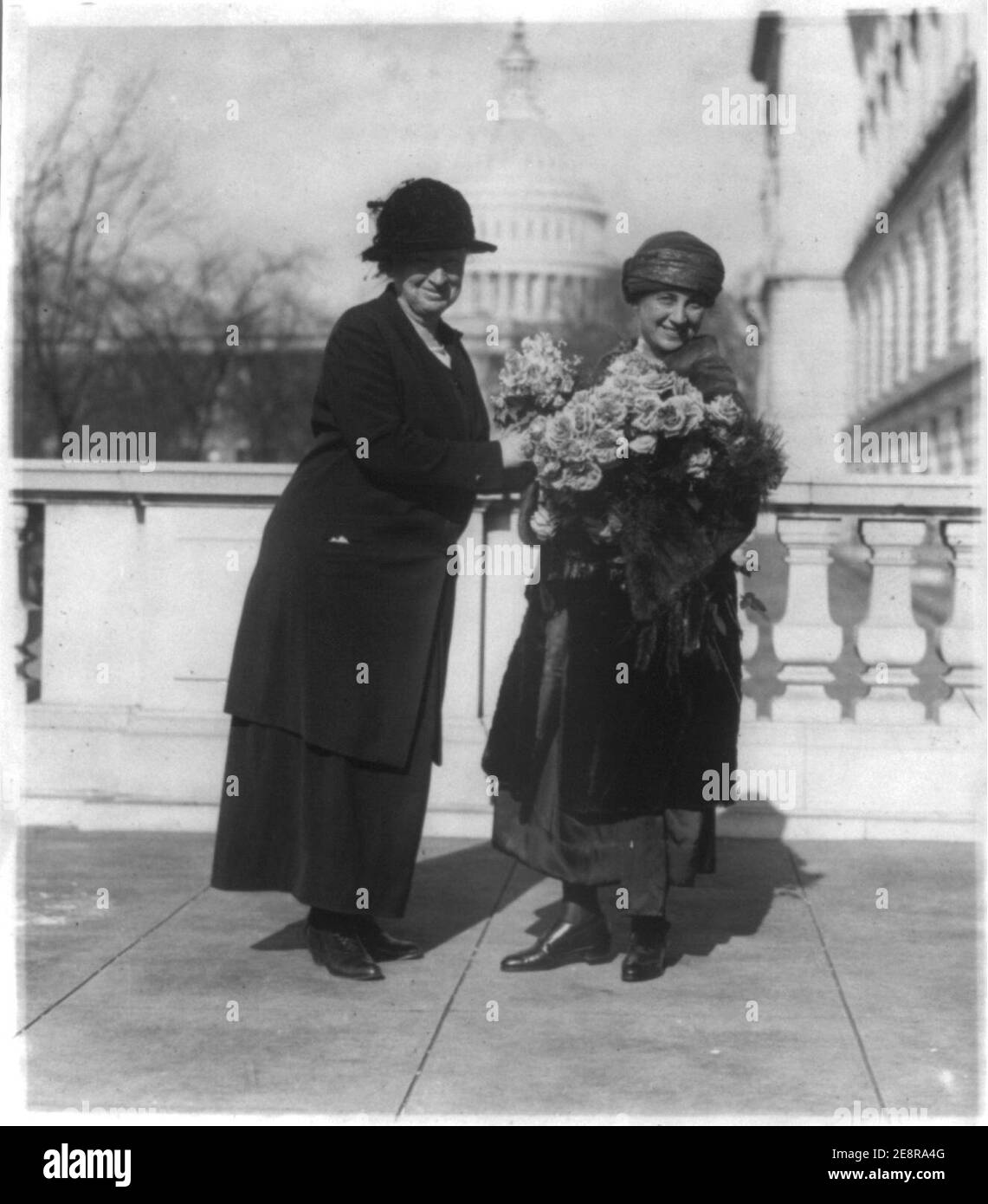 Miss Alice Robertson of Okla. presenting her new collegue (sic), Mrs. Winifred Mason Huck with flowers on the latter's arrival at the House Office Building Stock Photo