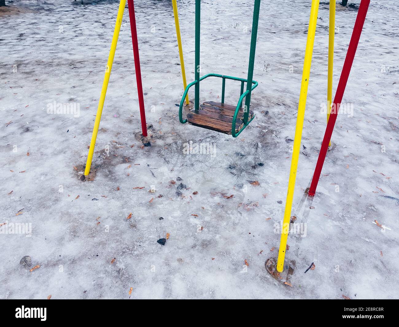 Close up of children's swing in early spring. Wet swing on playground in  slushy weather with melted snow Stock Photo - Alamy