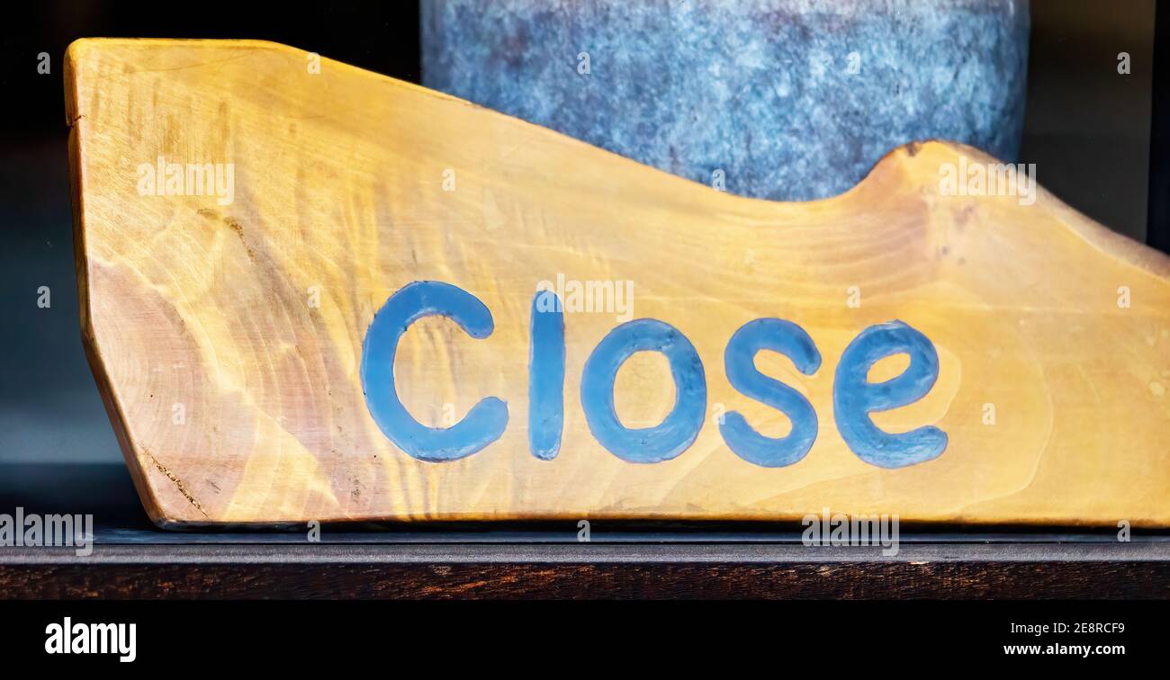 A wooden close sign, behind the window of a closed shop Stock Photo - Alamy