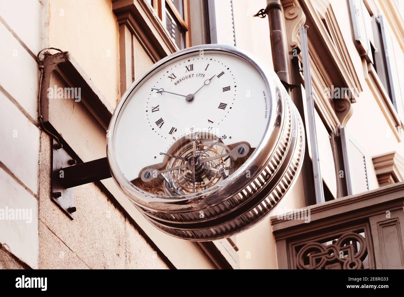 Vintage street clock with roman numerals hanging on the wall of