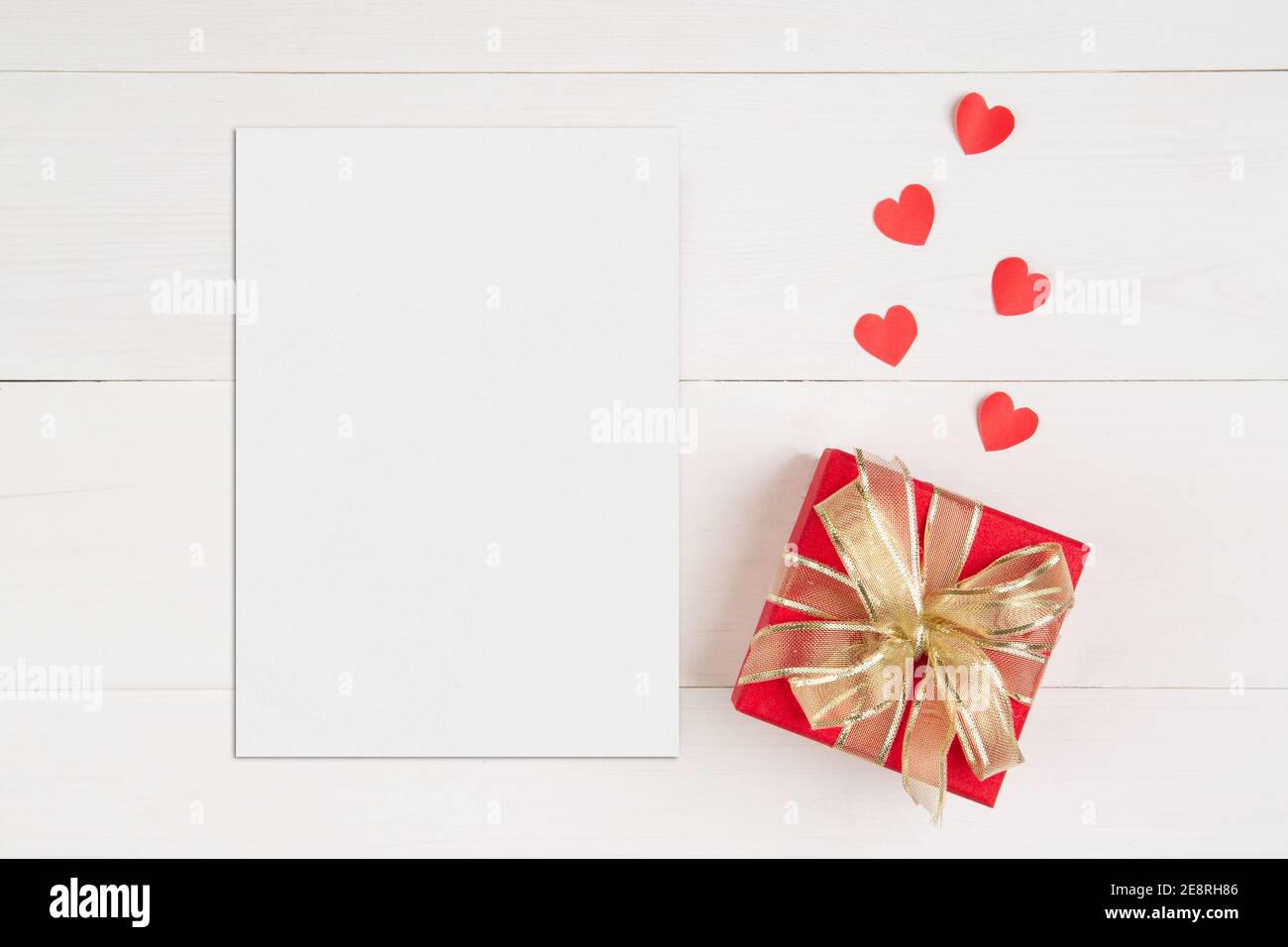 Blank postcard size a5 and letter and gift box and heart shape on wooden table, mockup greeting card and template, decoration with romantic, celebrati Stock Photo