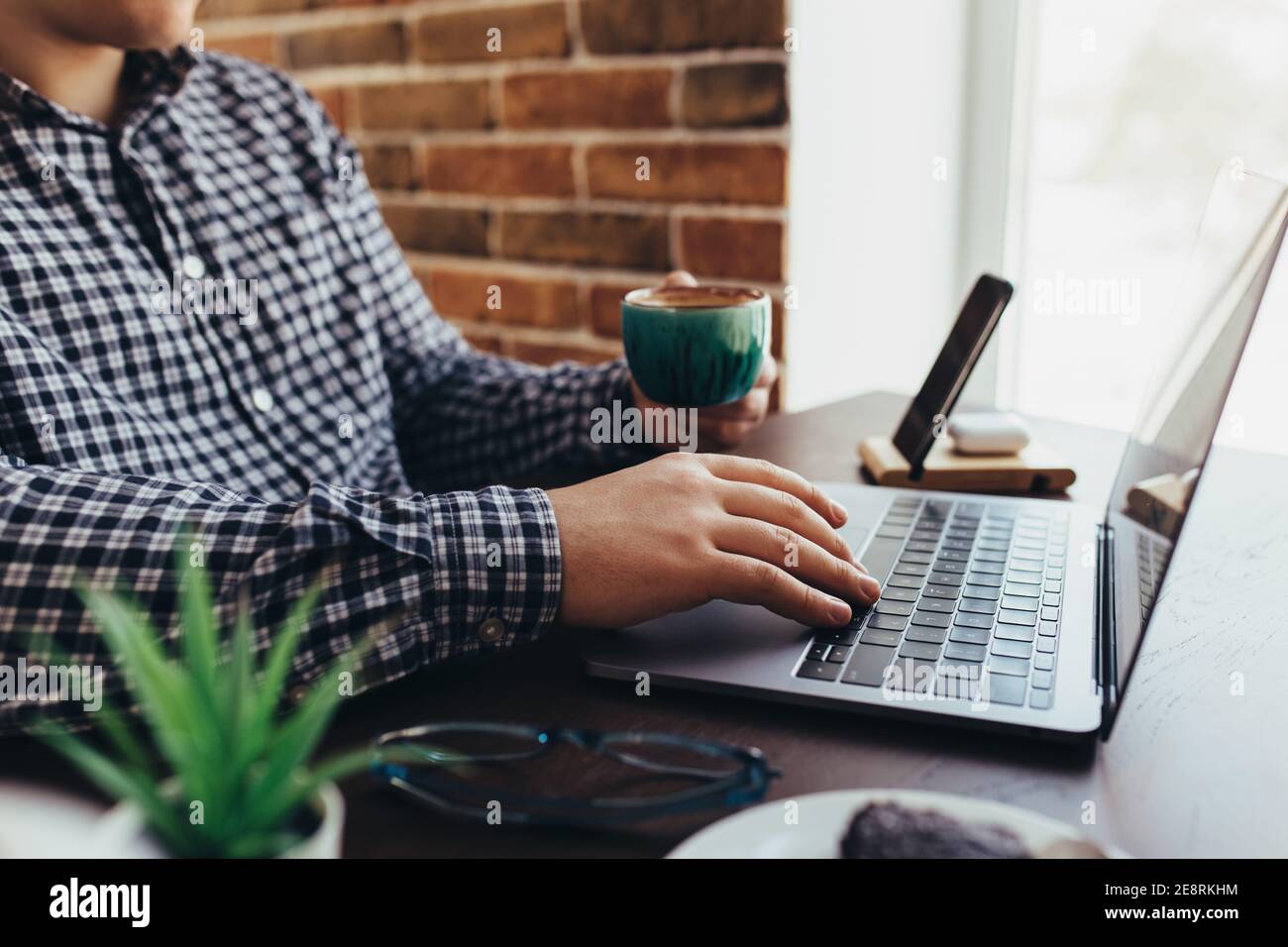 Man working at the laptop with a cup of coffee at home. Blurred background Stock Photo