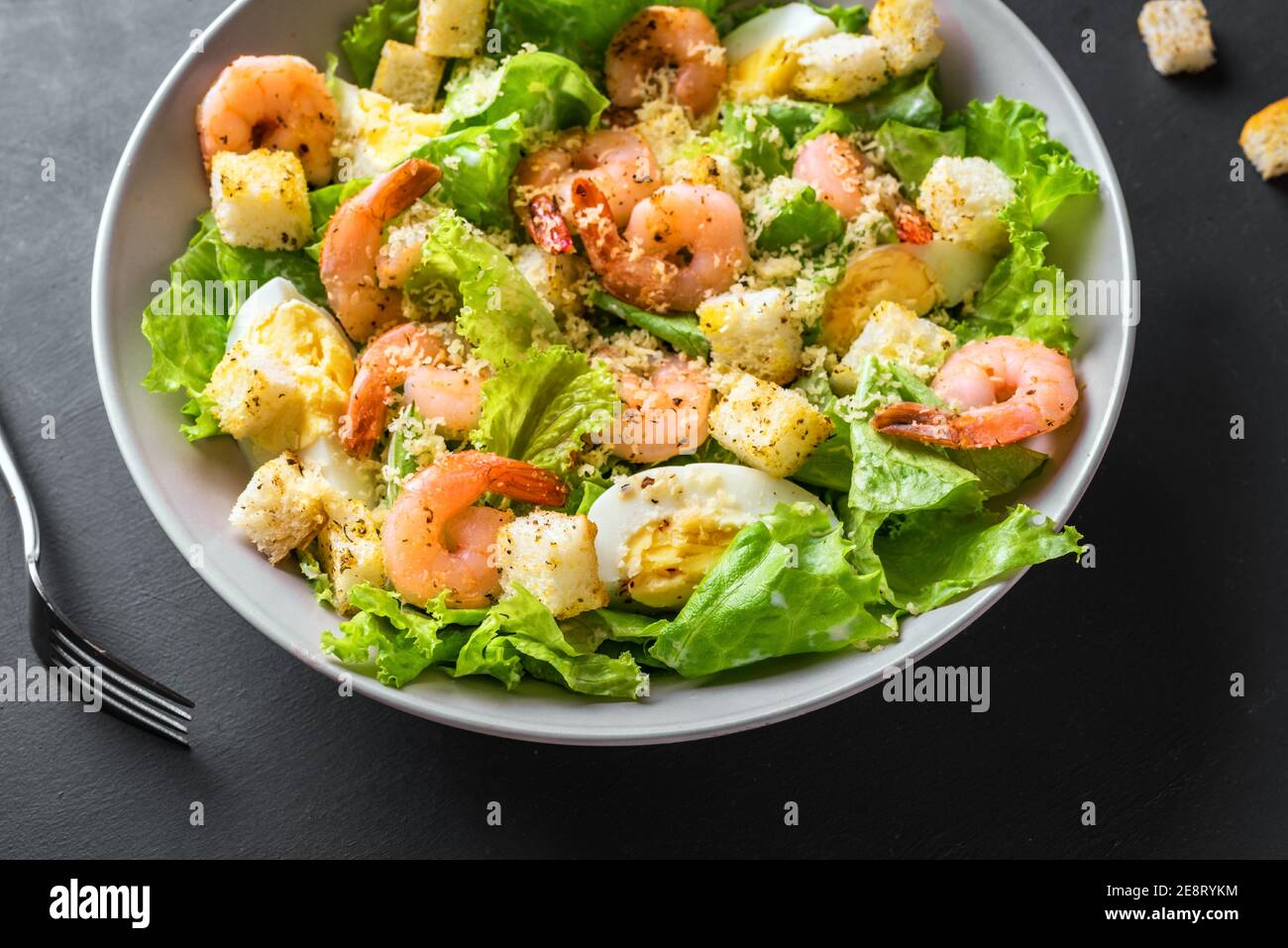 Shrimp Salad. Seafood Caesar Salad on black background, close up. Stock Photo