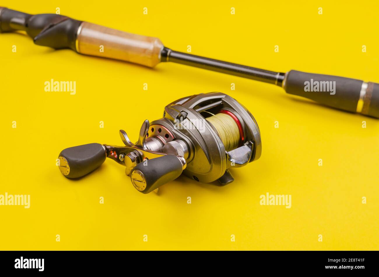 https://c8.alamy.com/comp/2E8T41F/fishing-rod-and-reel-on-a-yellow-background-casting-rod-with-a-multiplier-reel-fishing-tackle-selective-focus-2E8T41F.jpg