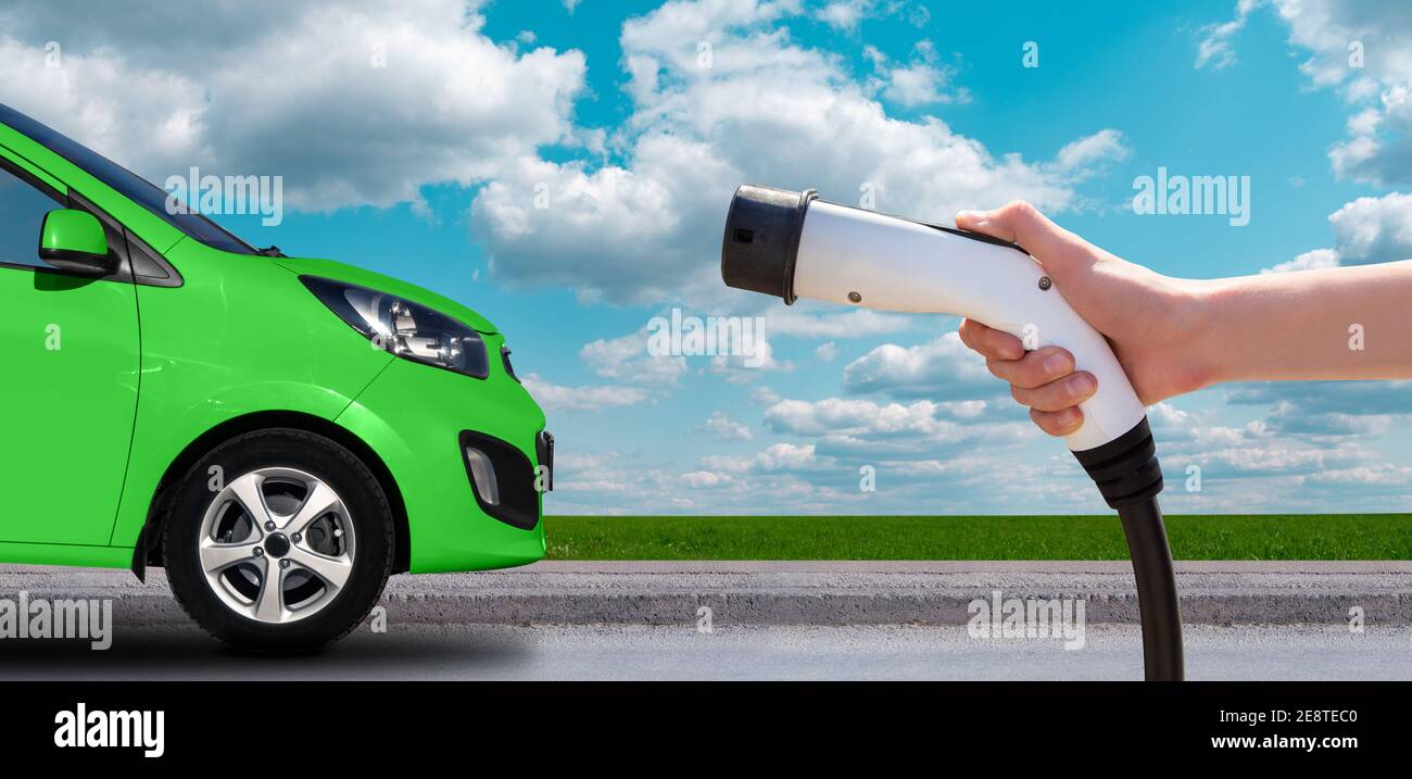 Hand with charger on a background of electric car Stock Photo