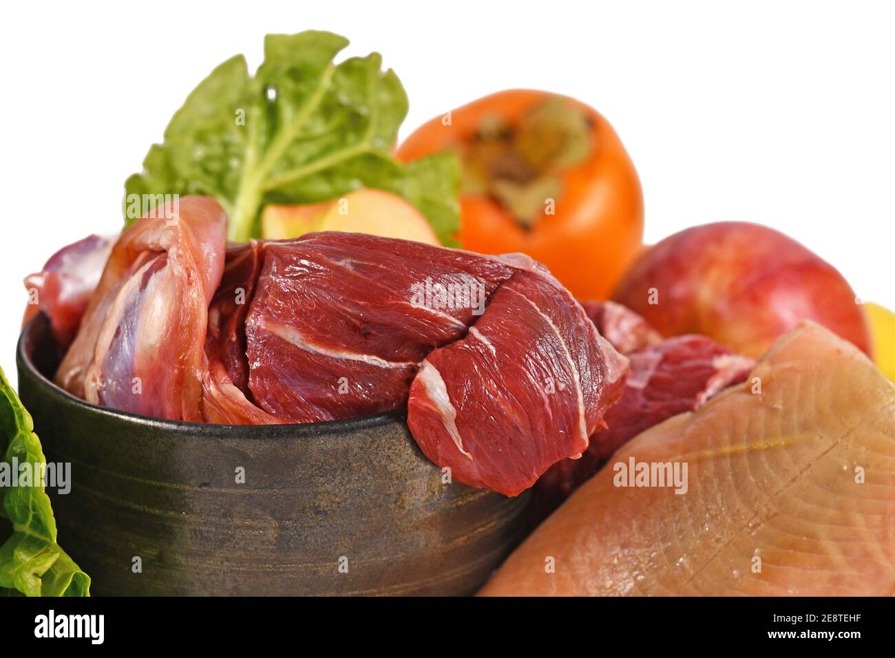 Close up of dog bowl with mixture of biologically appropriate raw food containing meat chunks, fish, fruits and vegetables isolated on white backgroun Stock Photo