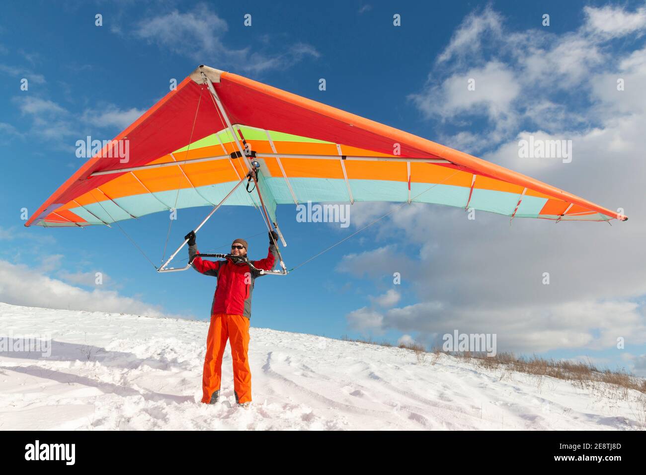 Happy man holding colorful hang glider wing on a slope. Learning to fly Stock Photo