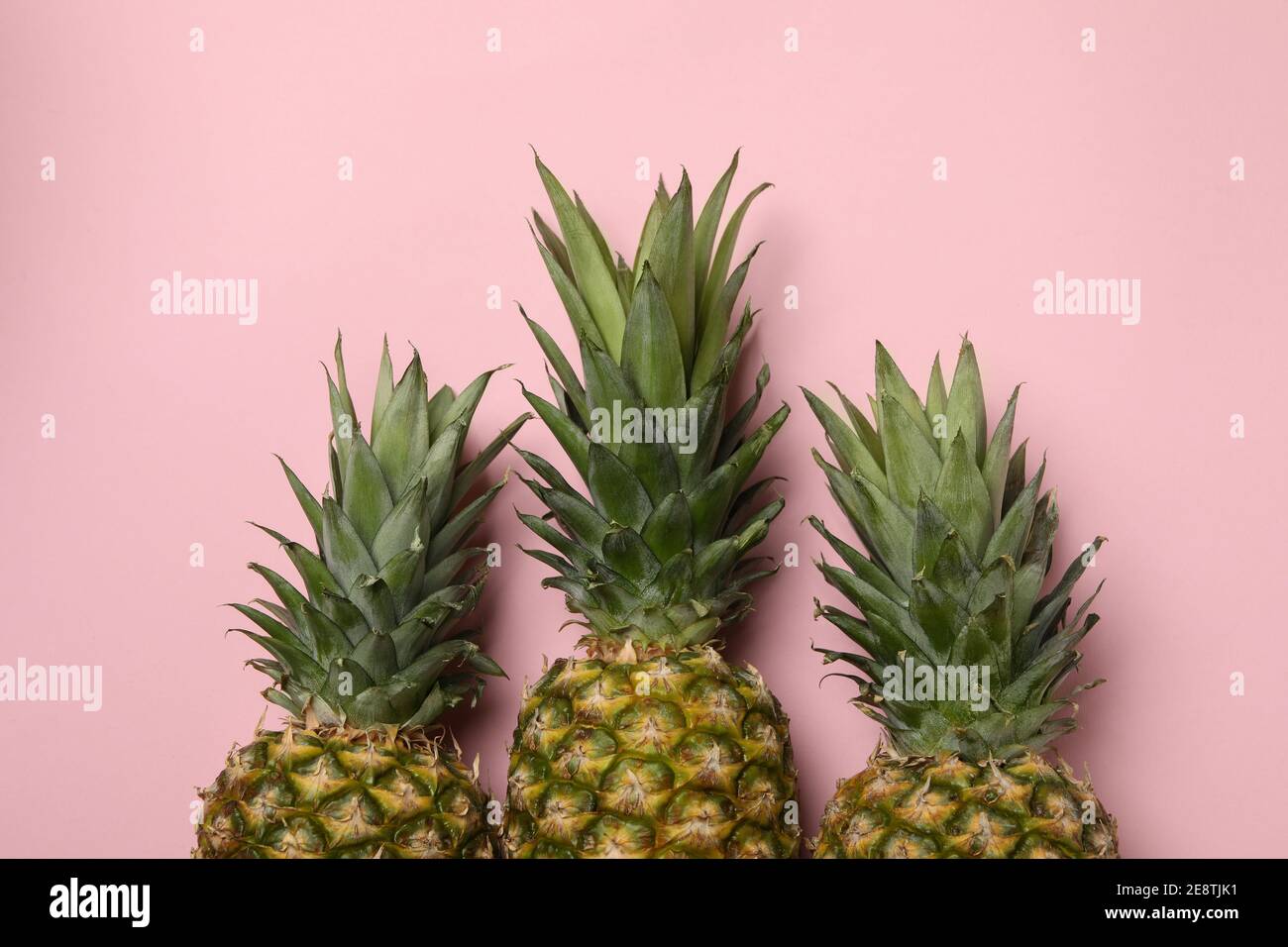 Three tasty ripe pineapples on pink background Stock Photo