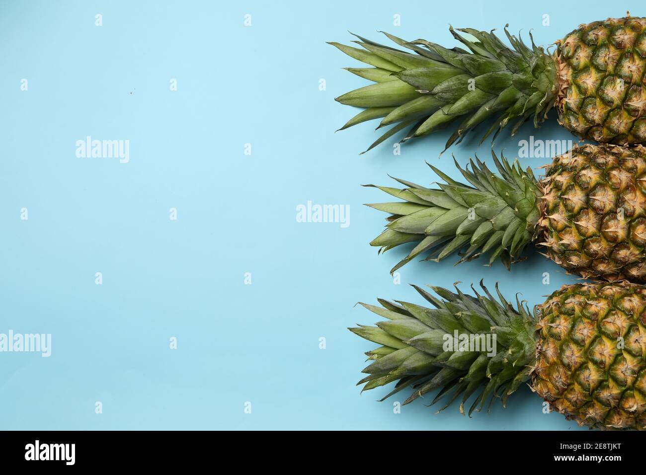 Three tasty ripe pineapples on blue background Stock Photo