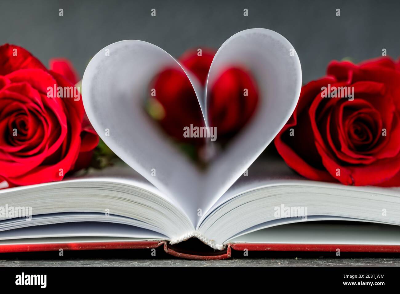 Hearth made with book pages. Valentine day concept with red roses ...