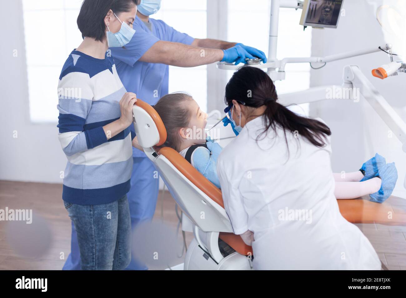 Kid getting cavity treatment from dentist sitting on dental chair wearing bib. Dentistry