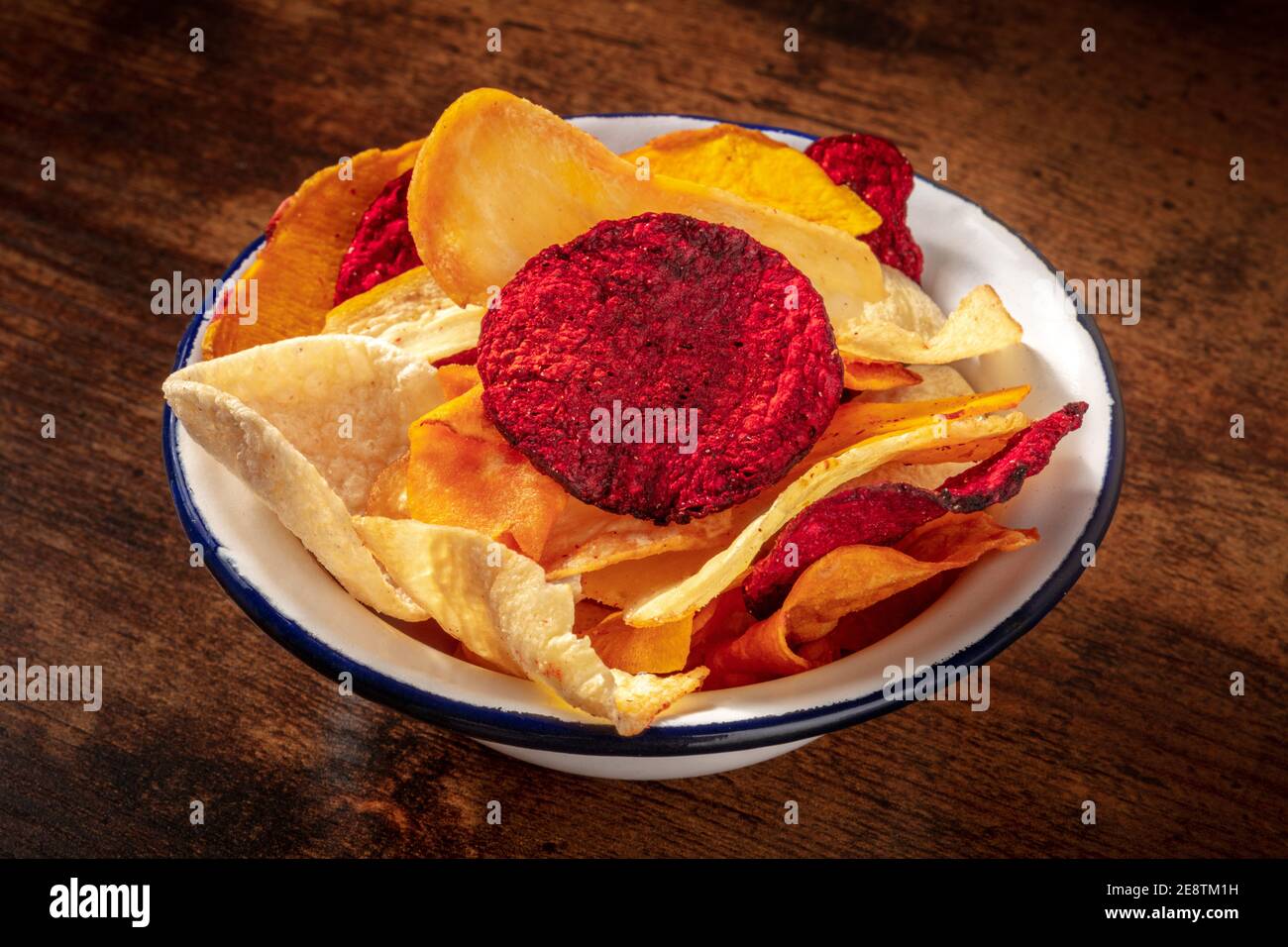 Vegetable chips in a bowl, a healthy vegan snack on a dark rustic wooden background Stock Photo