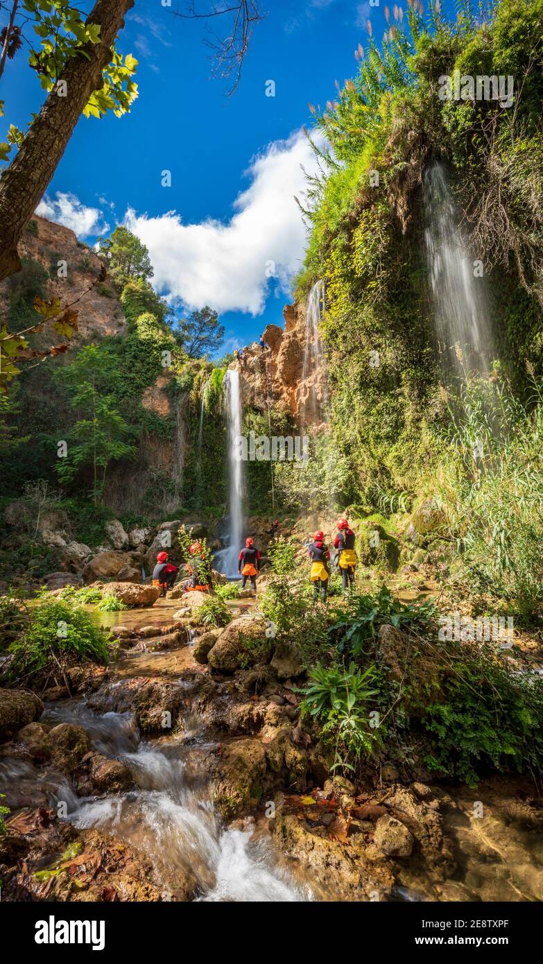 Unrecognizable people enjoy waterfall descent using ropes Stock Photo