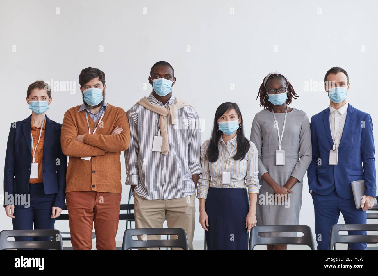Multi-ethnic group of business people wearing masks and looking at ...