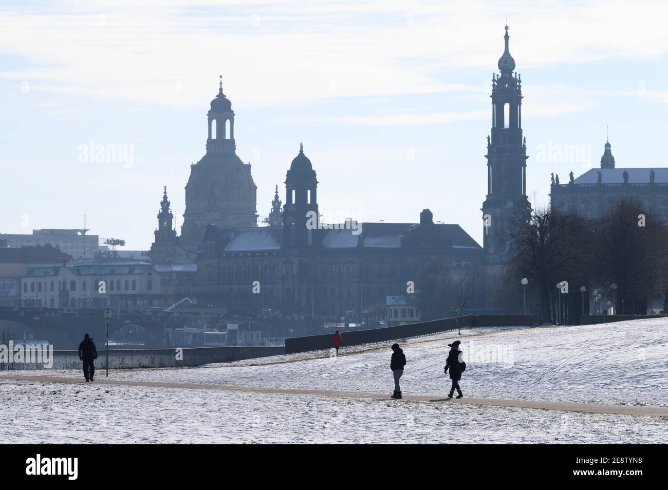 01 February 2021, Saxony, Dresden: Passers-by walk through the snow on the banks of the Elbe against the backdrop of the Old Town with the Frauenkirche (l-r), the Ständehaus and the Catholic Hofkirche. Photo: Sebastian Kahnert/dpa-Zentralbild/dpa Stock Photo