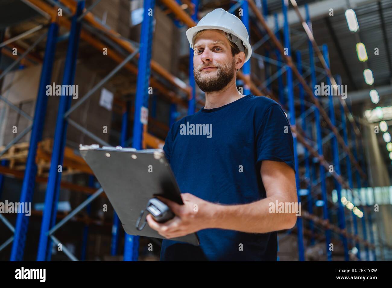 young-warehouse-manager-checking-goods-using-a-clipboard-in-a-warehouse