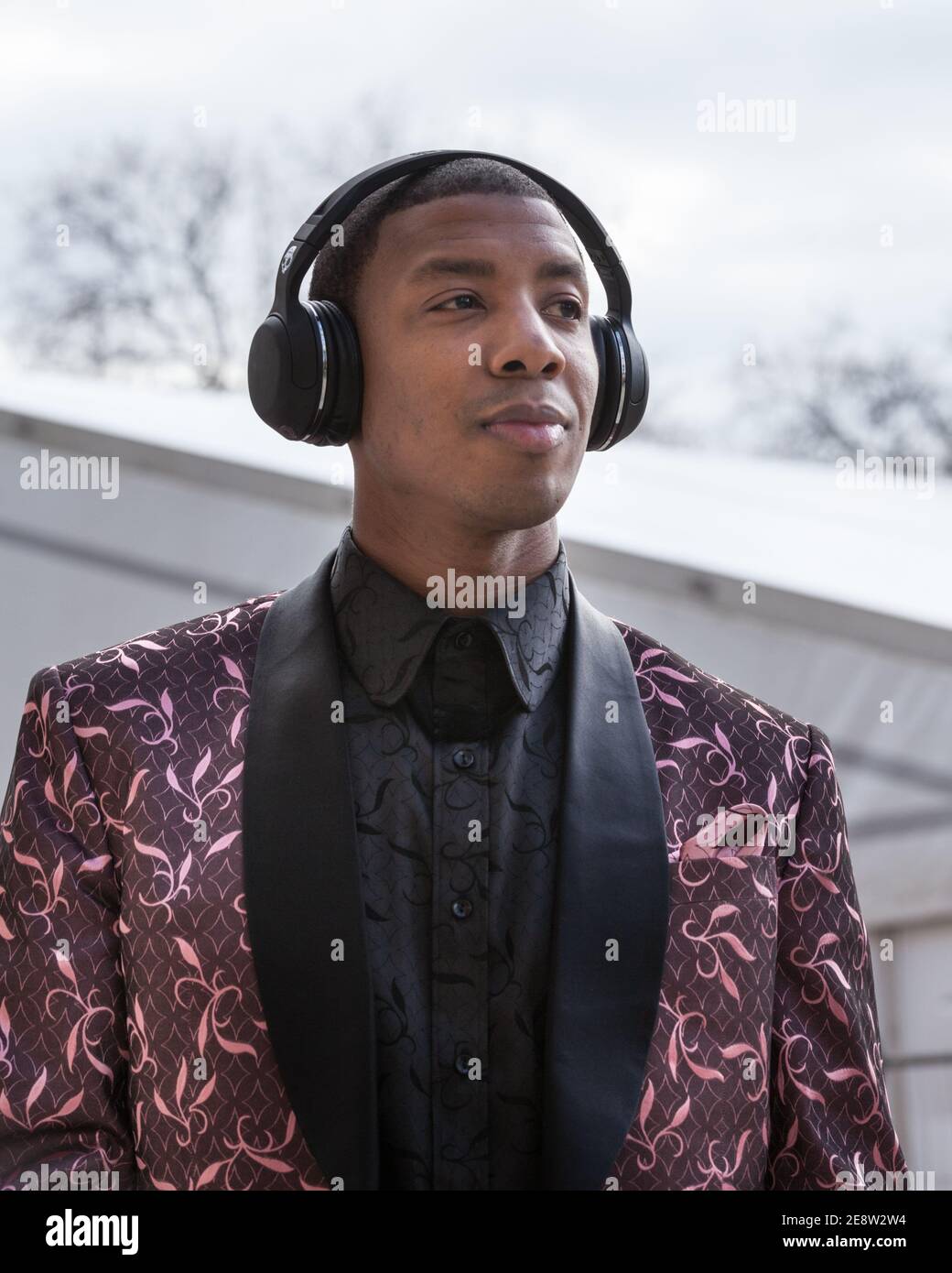 Young black male fashion lover with trendy ear phones in stylish suit outside London Fashion Weekend, Chelsea, London, UK Stock Photo