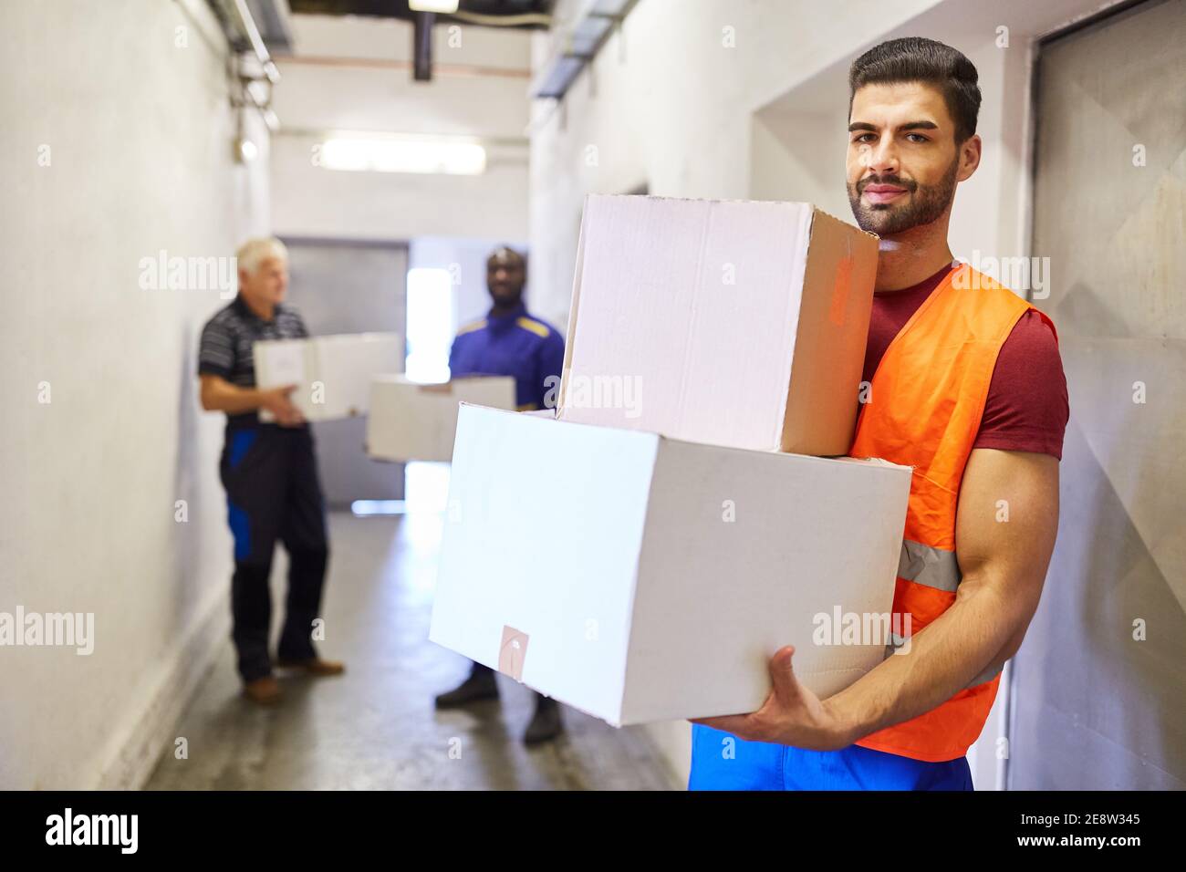 Worker with safety vest carries packages to the warehouse of a factory or shipping company Stock