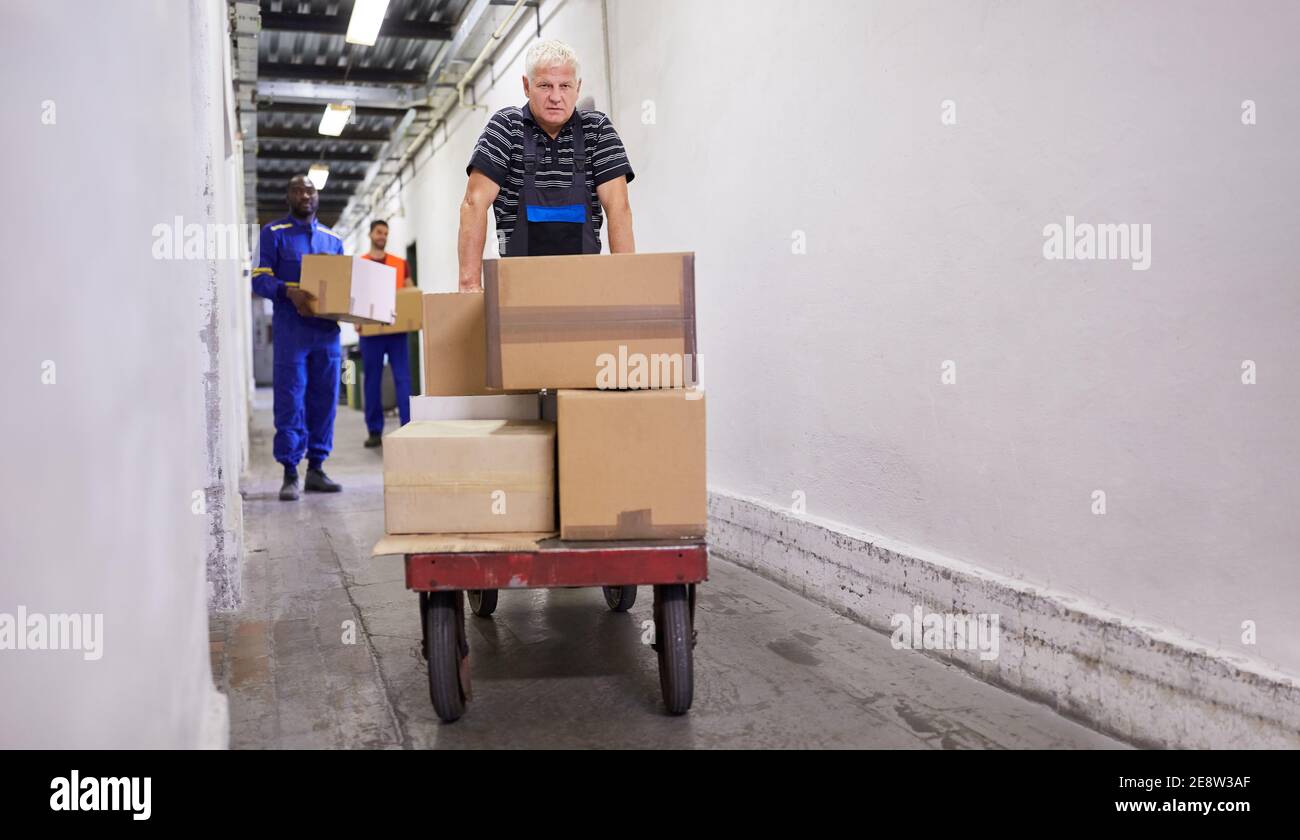 Worker pushes many packages on push carts to the goods