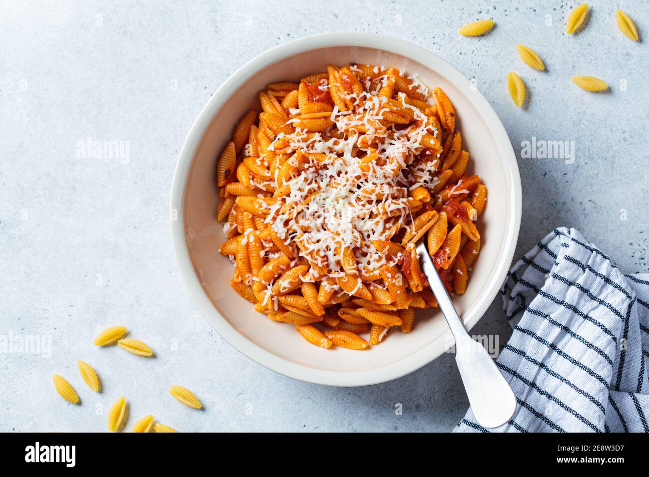 Gnocchetti sardi pasta in tomato sauce with cheese, gray background. Italian food concept Stock Photo