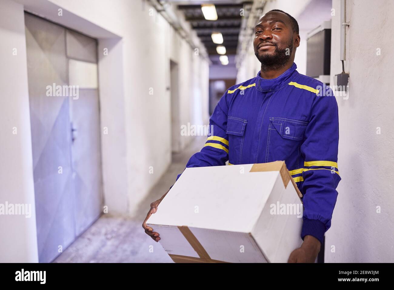 African worker as a temporary worker carries cardboard boxes through