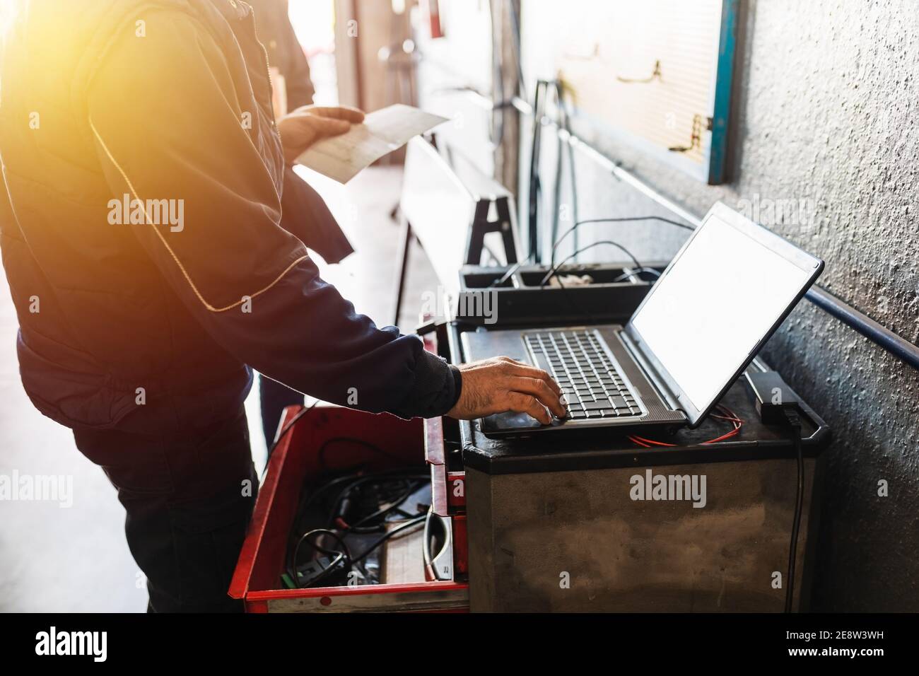Mechanic diagnosing the car on a computer. Sunlight effect. Automotive ...