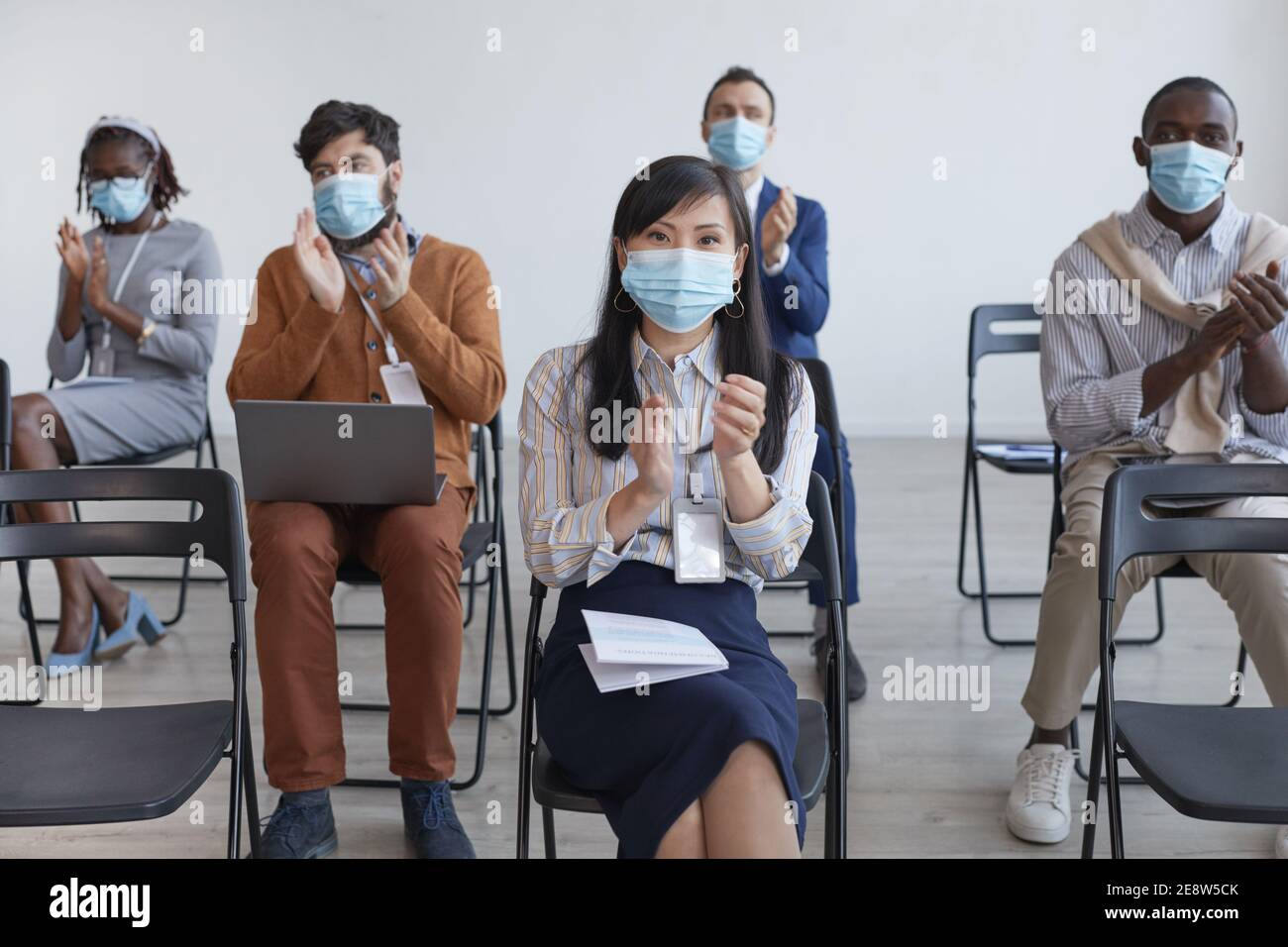 Multi-ethnic group of business people wearing masks and applauding with ...