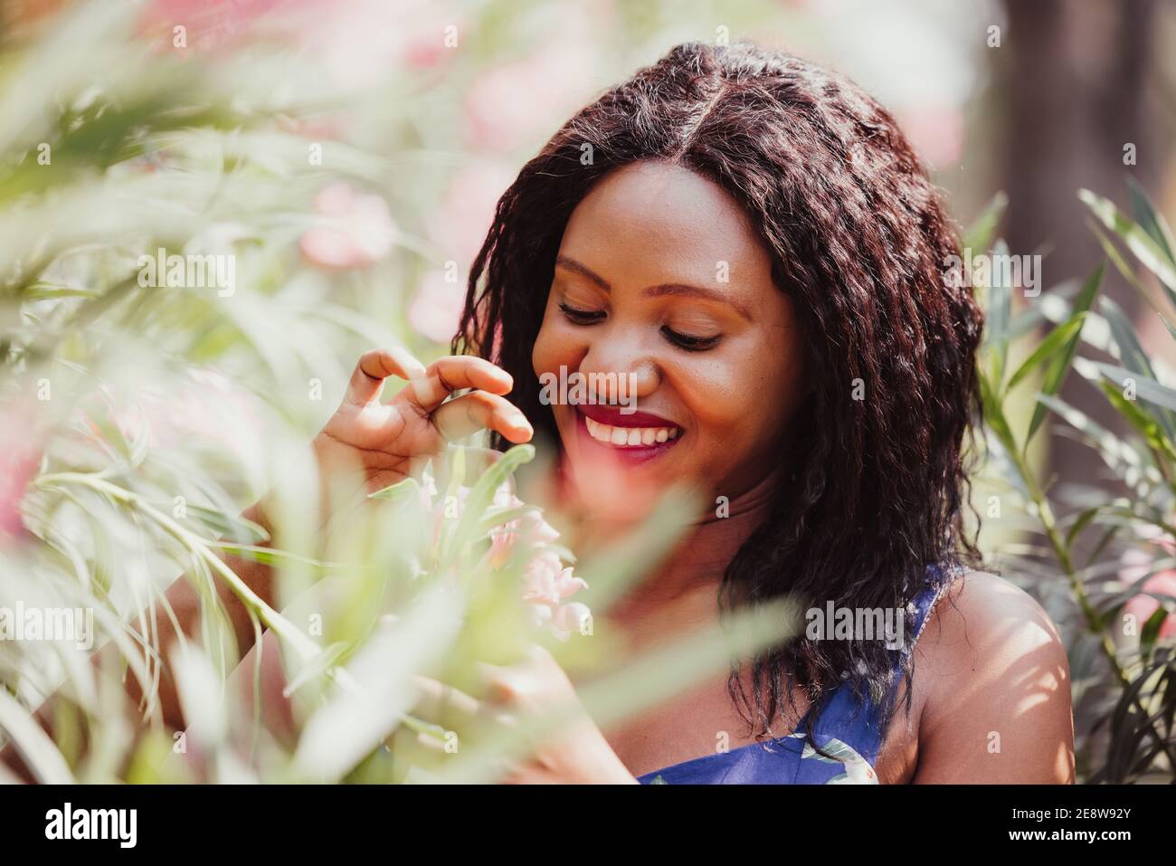 Content Black Woman Smelling Flowers in Park Stock Photo - Alamy