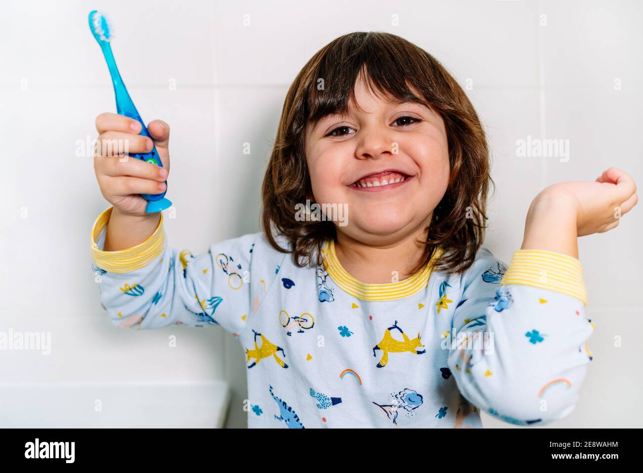 child very cheerful after brushing teeth with a toothbrush with pajamas