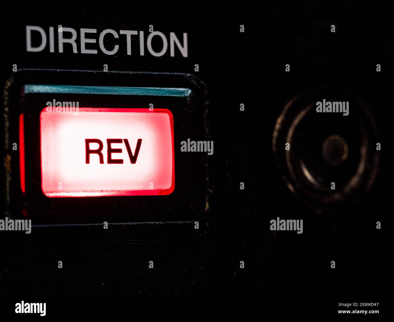 Illuminated 'Rev(erse)' button on a DJ mixing deck. Stock Photo