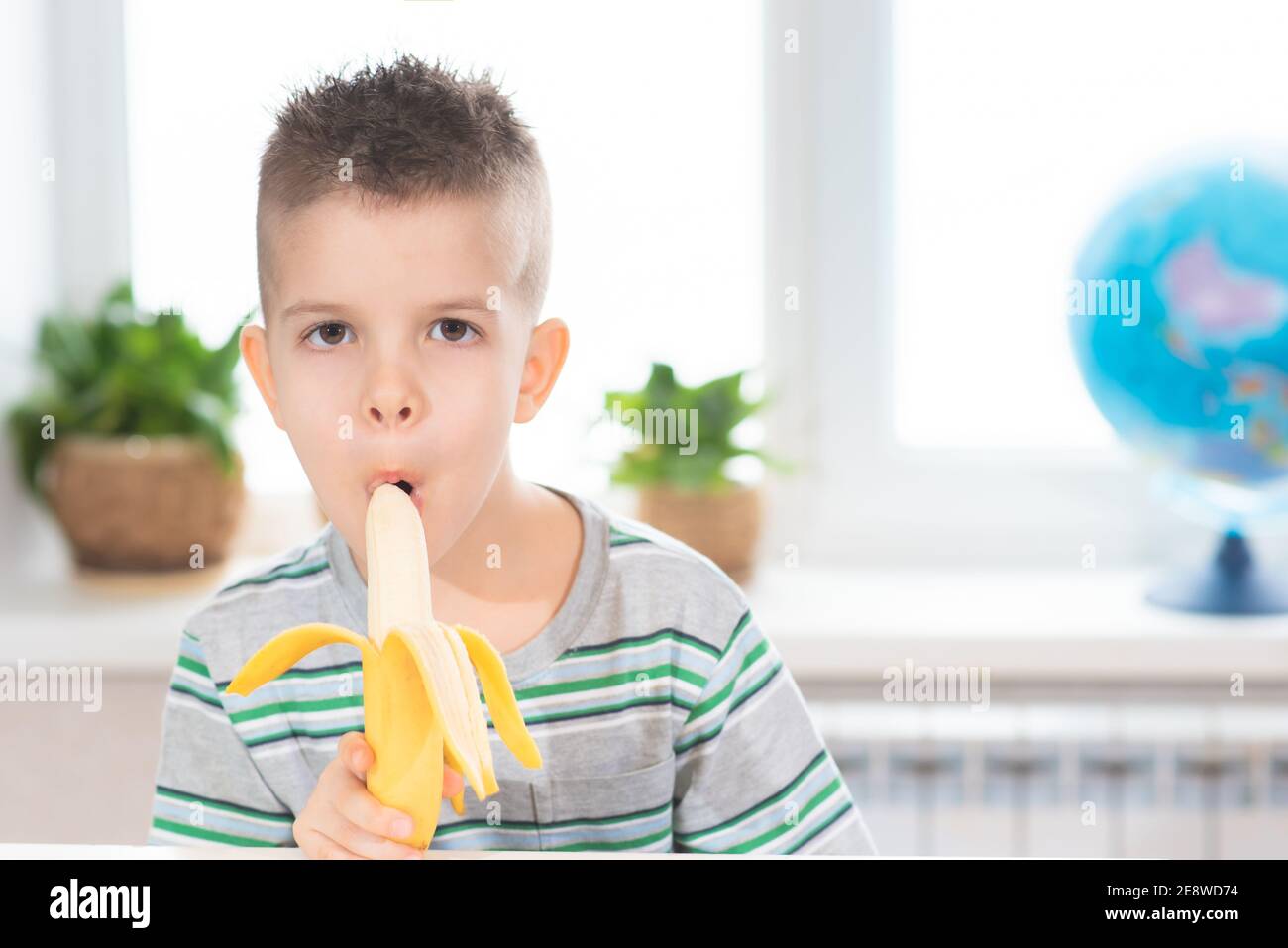 Handsome child eating banana in his room Stock Photo