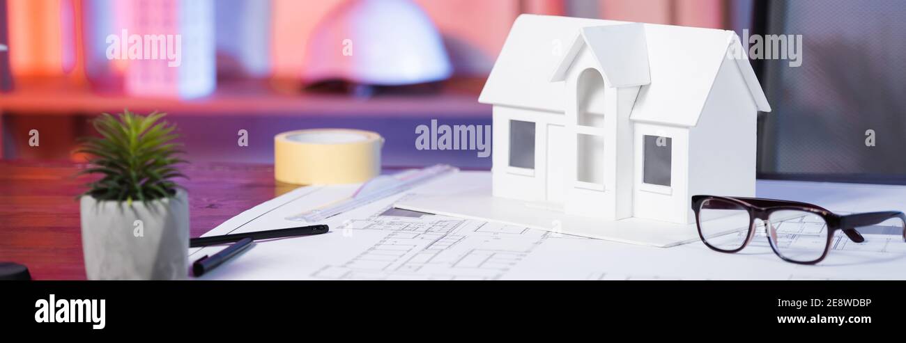 house model near eyeglasses and blueprint on desk in architectural agency, banner Stock Photo