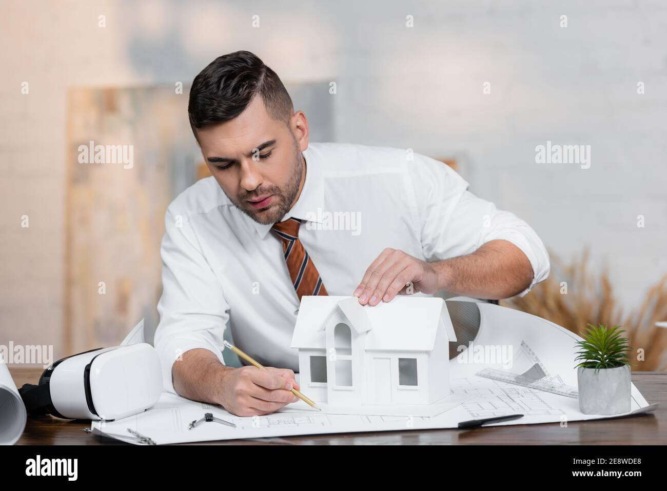 concentrated architect drawing on blueprint near house model Stock Photo