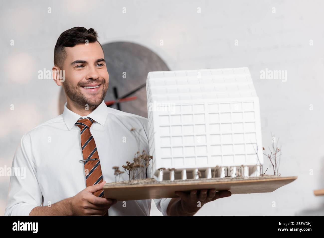 happy architect holding house model in architectural agency Stock Photo