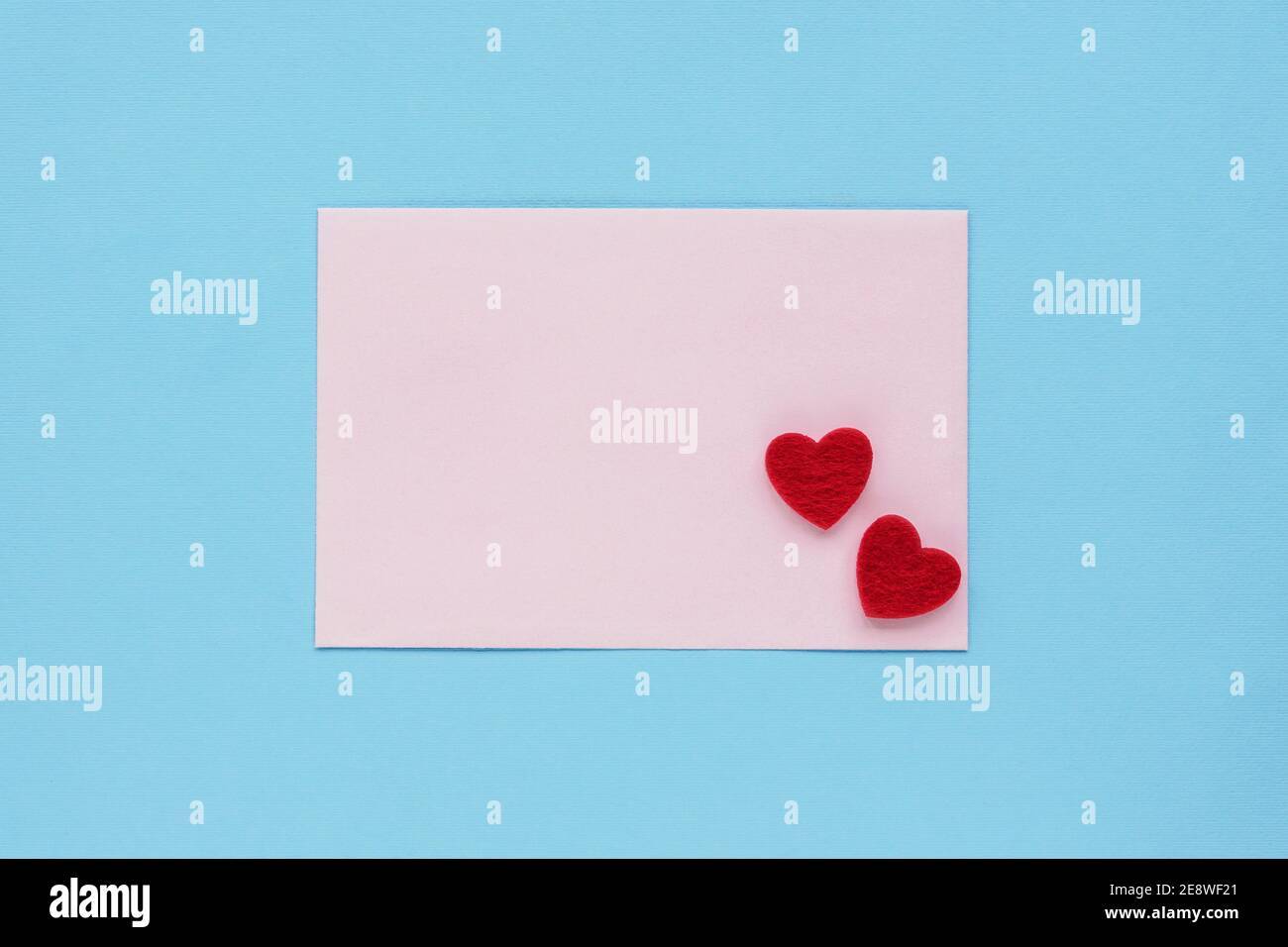 Pink envelope with two red hearts on a blue background, top view, flat lay. Valentines day concept, 14 february. Stock Photo